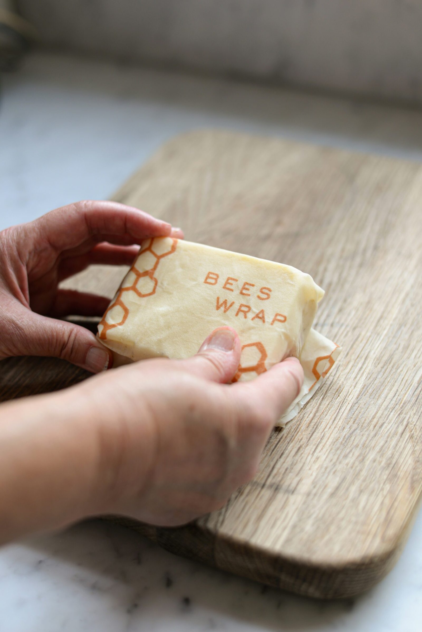 a person holding a piece of cheese on a cutting board